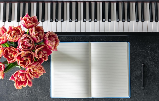 Piano boeket van tulpenbloemen en notitieboek op een donkere achtergrond top view