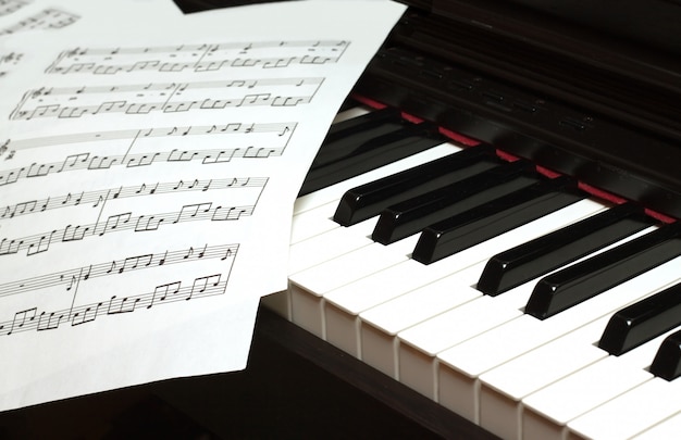 Piano keyboard and music sheets close up