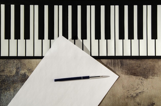 Foto tastiera di pianoforte, penna e carta bianca. il concetto di comporre musica, canzoni, creatività, apprendimento.