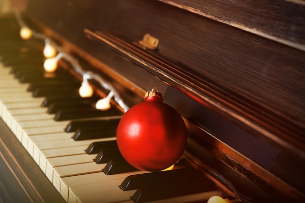 Piano keys decorated with decoration lights and red ball, close up