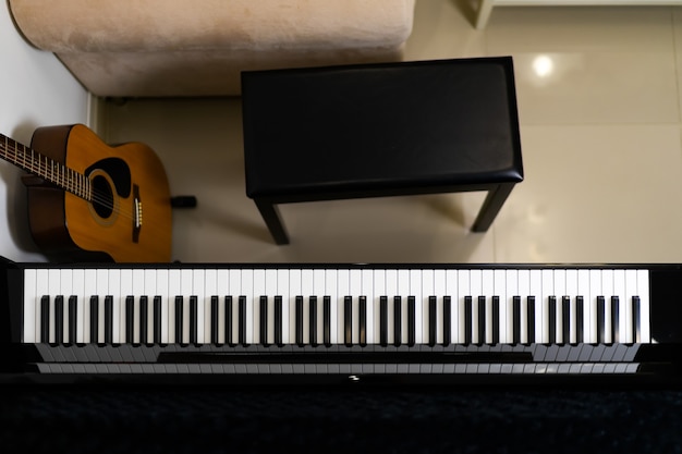 Piano top view with piano chair and guitar