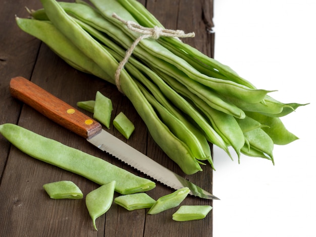 Piattoni green beans with a knife on wooden table close up