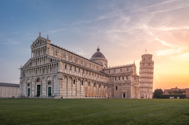 Piazza del Duomo met schuine toren en Cattedrale di Pisa tegen zonsopgang kleurrijke hemel Pisa Italië