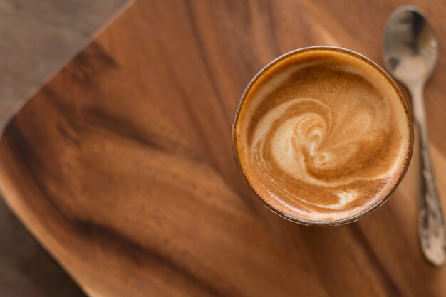 Piccolo Latte-kunst in klein glas op houten bureau