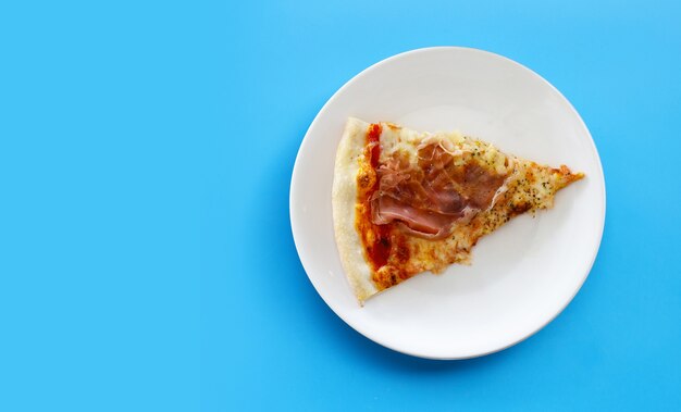 Pices of Pizza on white plat on blue background.