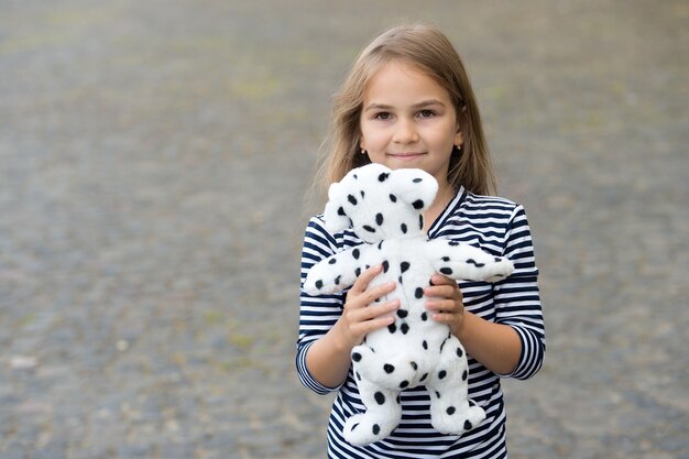 最高のものを選んでください。幸せな女の子は屋外でおもちゃの犬と遊ぶ。玩具屋。ゲームと活動。小児発達。幼児教育。子供の頃に遊んでいます。ベビー用品店。ギフトショップ、コピースペース。