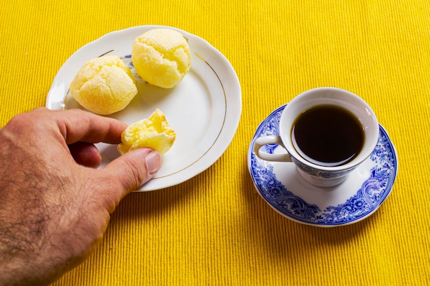 Picking up the brazilian cheese bread and coffee cup and on the yellow mat