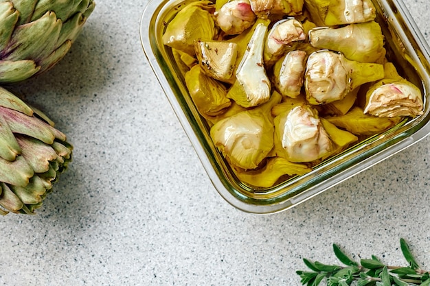 Pickled artichoke with garlic in glass bowl on the table