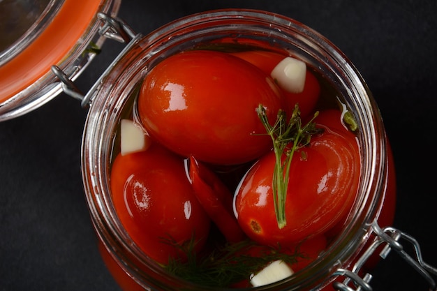 Photo pickled cherry tomatoes in a glass jar.