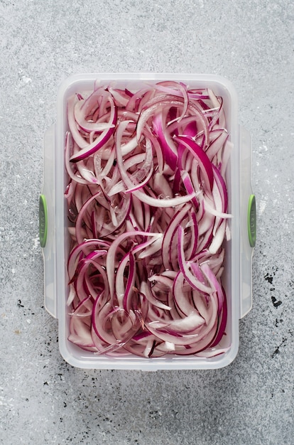 Pickled chopped red onion in vinegar in a plastic container