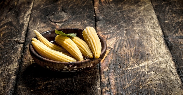 Pickled corn in a bowl on wooden table.