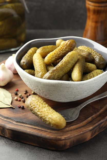 pickled cucumbers in bowl fork and spices on grey table