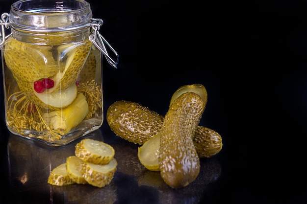 Pickled cucumbers in a glass jar and on a wooden board.\
fermented food on a gray background. copy space.