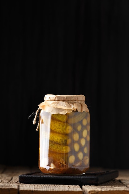 Pickled cucumbers in a jar on a dark background with place for text closeup