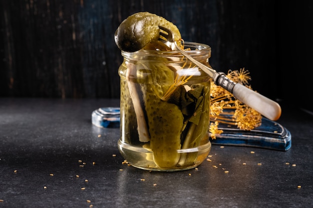 Pickled cucumbers in a jar on a dark gray stone background