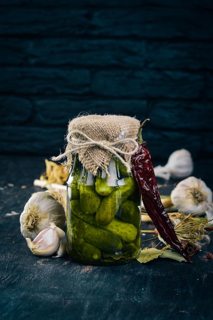 Pickled cucumbers in a jar Stocks of food Top view On a wooden background Copy space