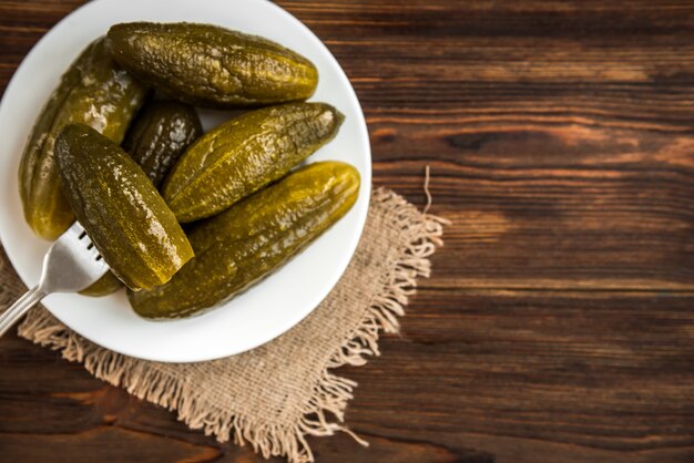 Pickled cucumbers on white plate on wooden rustic