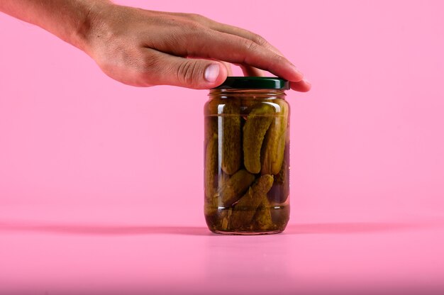 Pickled cucumbers with herbs and spices on pink wall