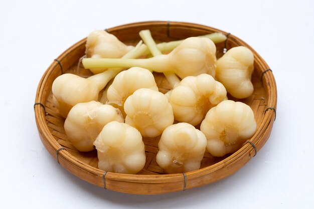 Pickled garlic in bamboo basket on white background.