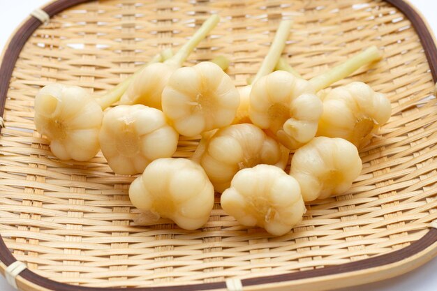 Pickled garlic in bamboo basket on white background.