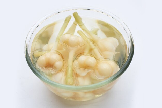 Pickled garlic in glass bowl on white background.