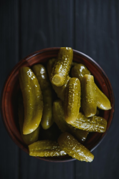 Pickled gherkins or cucumbers in bowl on wooden rustic table from above