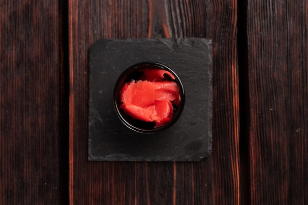 Pickled ginger in bowl top view wooden background