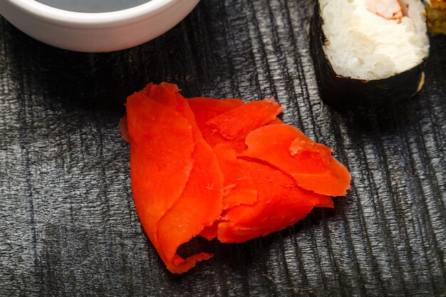 pickled ginger, rolla fragment on a black carved board. Horizontal photo