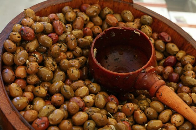 Pickled green olives and wooden scoop in a barrel