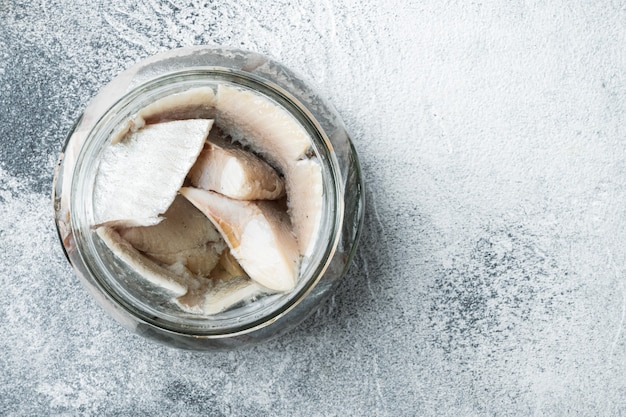 Pickled herring set, in glass jar, on gray