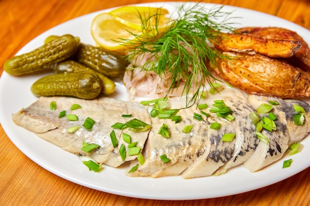 Pickled herring with pickles and herbs