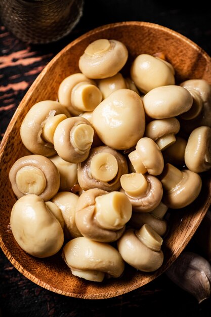 Pickled mushrooms in a wooden plate on the table