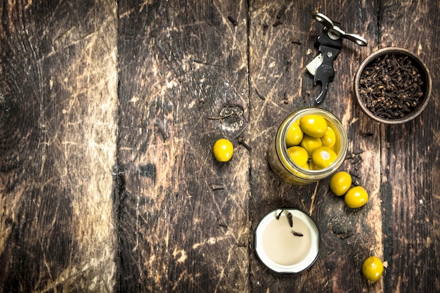 Photo pickled olives in glass jar on wooden table