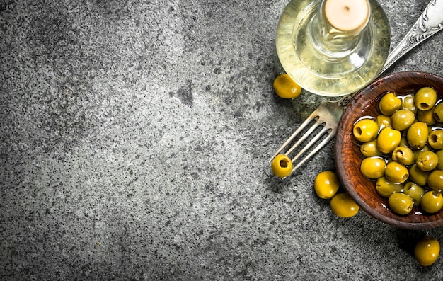 Photo pickled olives with olive oil on a rustic table.