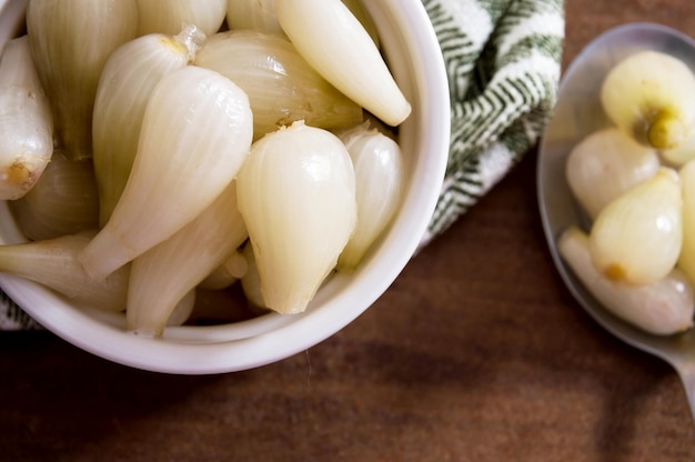 Pickled onions in bowl over cloth and spoon part on the side with onions out of focus