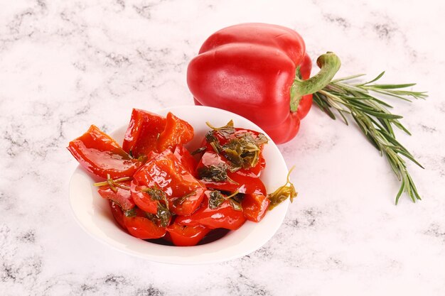 Pickled red bell pepper with herbs in the bowl