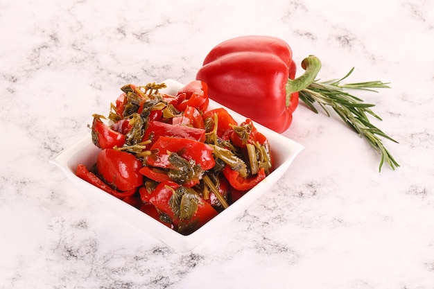 Pickled red bell pepper with herbs in the bowl