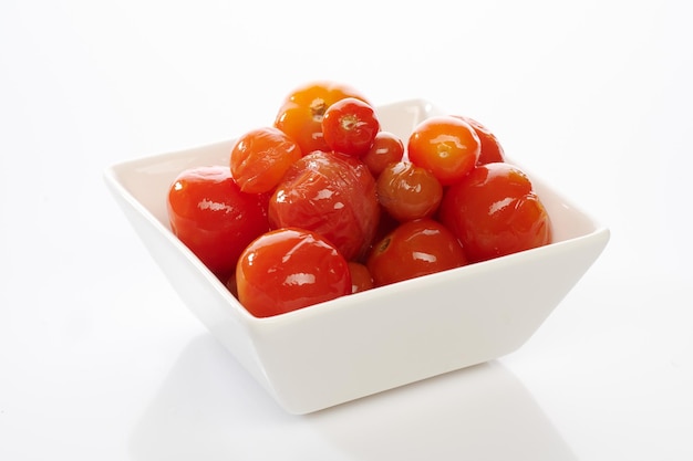 Pickled red tomatoes in bowl isolated on white background