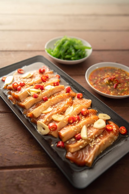 Pickled salmon with shoyu or soy sauce and spicy dipping sauce\
thai style food.