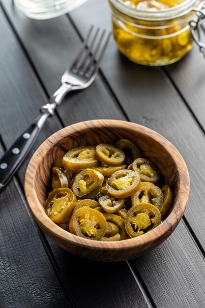 Foto jalapeno a fette marinato peperoni jalapeno verdi in una ciotola su tavolo di legno