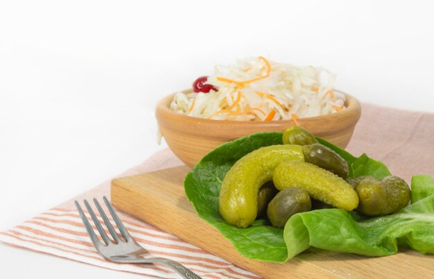 Pickled vegetables cucumbers with sauerkraut on a plate on the table background