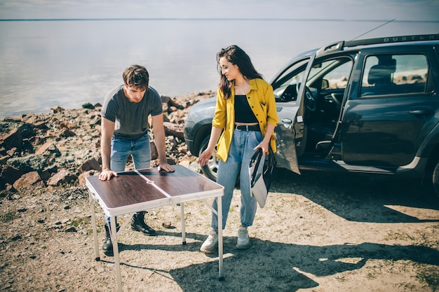 Picknick aan het water. Gelukkige familie op een roadtrip in hun auto. Man en vrouw reizen door de zee of de oceaan of de rivier. Zomerrit met de auto.