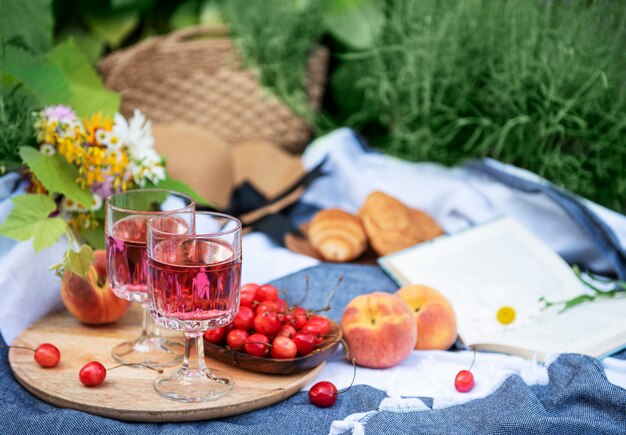 Picknick buiten in lavendelvelden. rose wijn in een glas, kersen en strohoed op deken