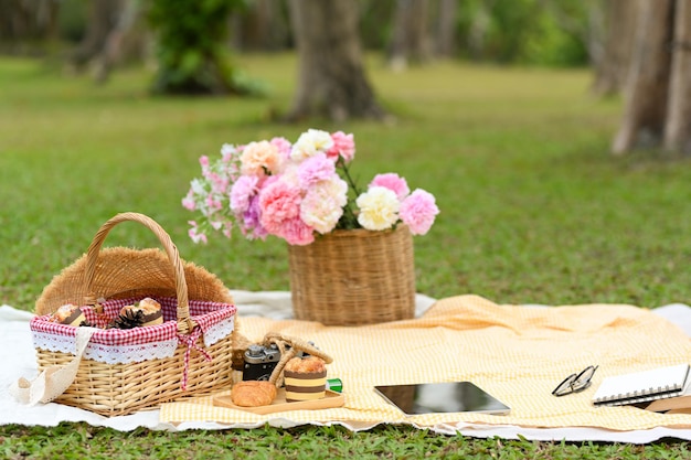 Picknick in de tuin Picknick rieten mand bloemboeket gebak en accessoires op picknickkleed