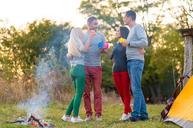 Picknick met vrienden bij het vuur. Bedrijfvrienden die een achtergrond van de stijgingspicknick hebben. Vrienden vertellen verhalen. Zomerpicknick. Veel plezier met vrienden