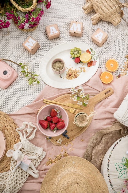 Picknick op het gras voor moederdag met fruit, argentijnse partner en bloemen op enkele dekens.