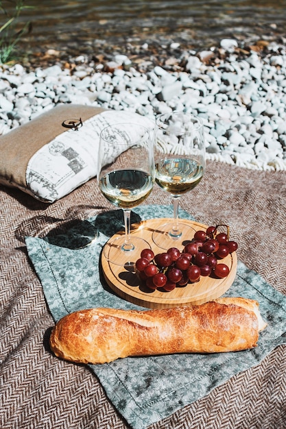 picknick op het strand met twee witte wijnglazen fles stokbrood kaas en druif