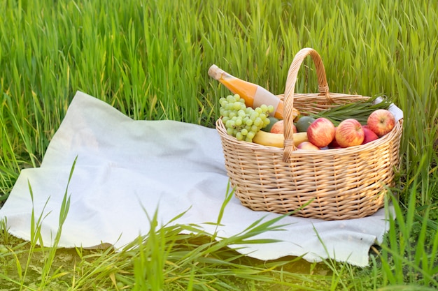 Picknick rieten mand met voedsel op gras in het veld