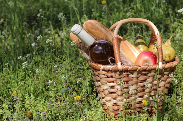 Picknick rieten mand met wijn, fruit en andere producten in het groene gras.