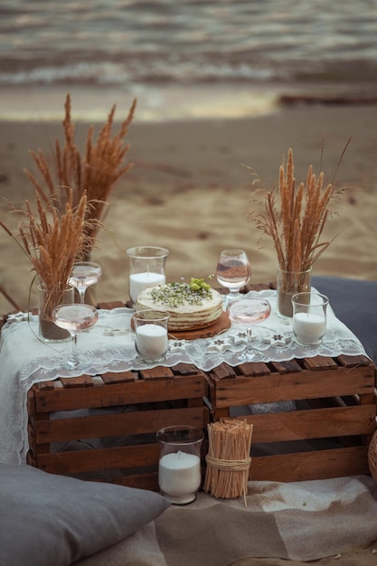 Picknick 's avonds bij zonsondergang aan de zandige kust van de zee of oceaan decor in boho en rustieke stijl